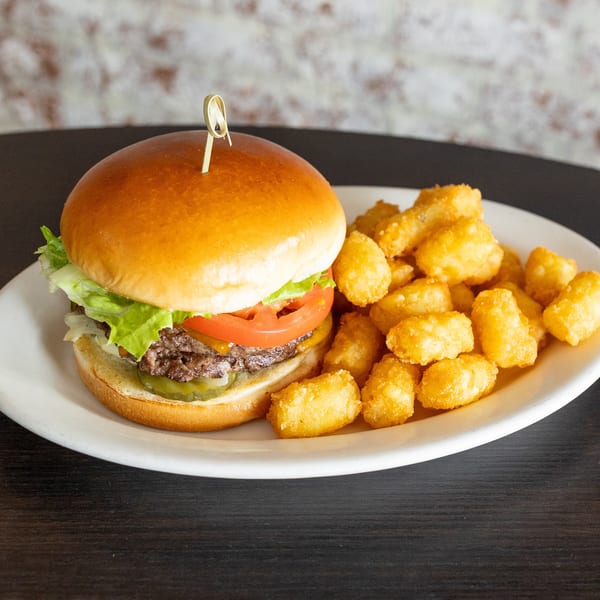 Cheeseburger with lettuce, tomato, and pickles, served with a side of crispy tater tots.