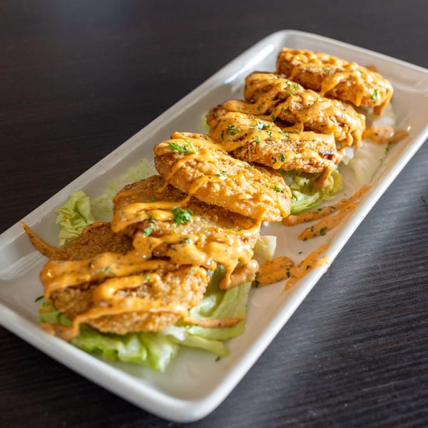 Fried chicken tenders drizzled with orange sauce and garnished with parsley, served on lettuce.